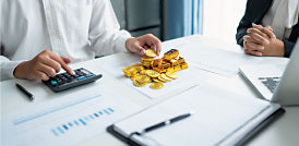 People reviewing gold jewelry at a table with a calculator and paperwork.